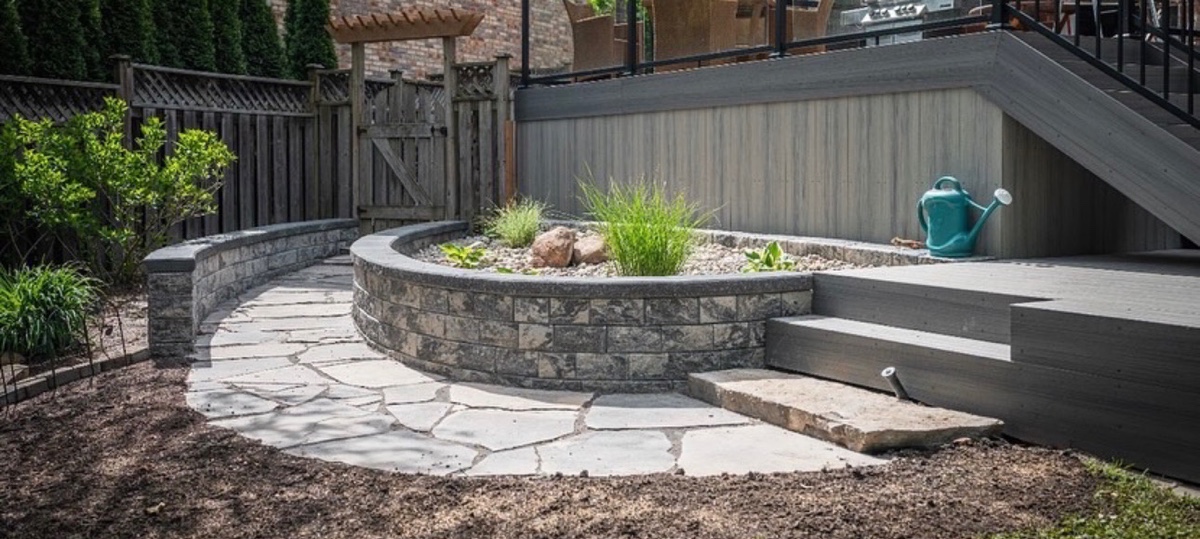 Curved stone planter wall and flagstone walkway