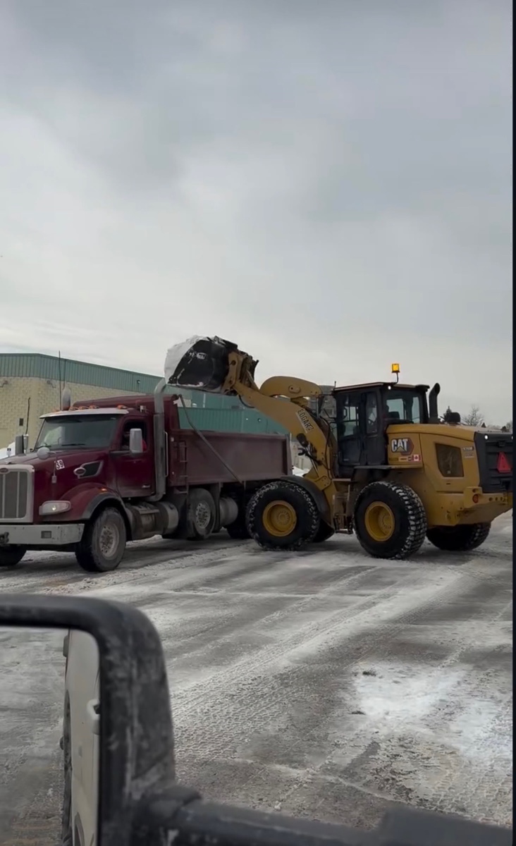 Loader loading a dump truck at a commercial winter site