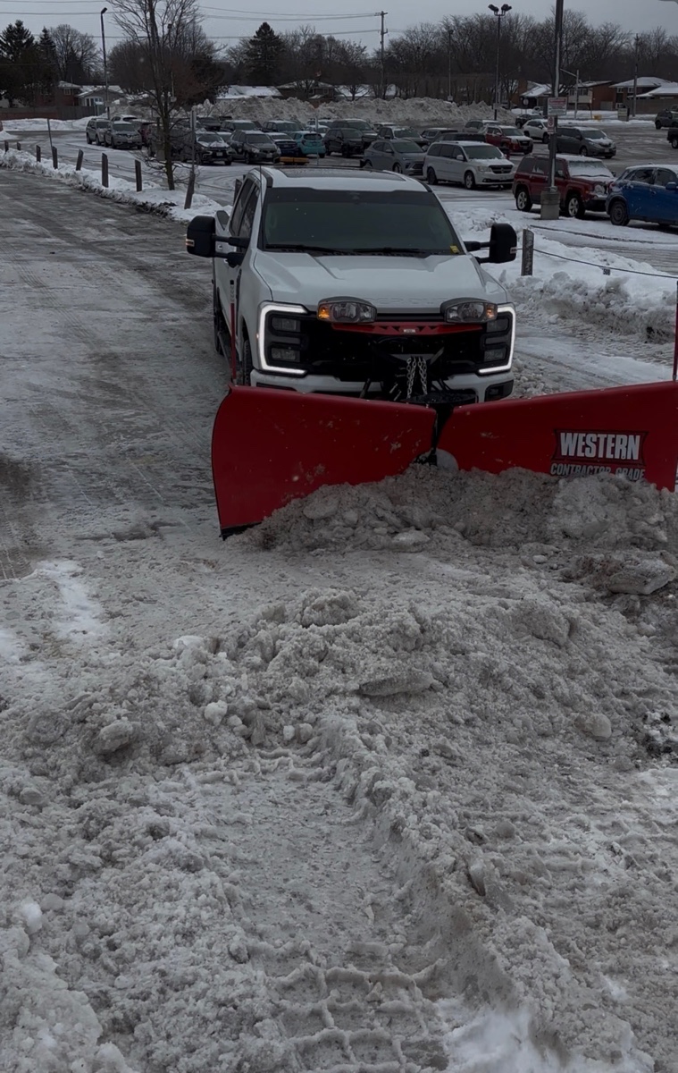 Brothers Landscaping plow truck clearing a commercial parking lot in winter